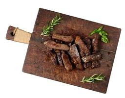 roasted piece of beef ribeye cut into pieces on a vintage brown chopping board. Well done photo