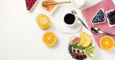 taza de negro café, un plato de harina de avena y fruta, miel y un vaso de Leche en un blanco mesa foto