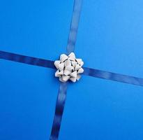 dark blue silk ribbon crossed on a blue background in the middle of a gray bow photo