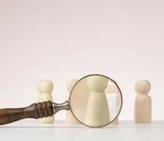 figurines of men on a white table and magnifying glass. Concept of searching for employees in the company, recruiting personnel, identifying talented photo