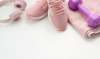 pair of textile purple sports sneakers, wireless headphones, a towel on a white background. Sportswear photo
