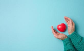 female hands holds red heart, blue background. Love and donation concept, copy space photo