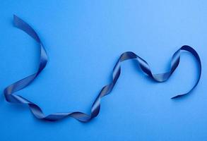 blue silk thin ribbon twisted on a blue background photo