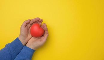 female hands holds red textile heart, blue background. Love and donation concept photo