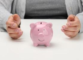 female hands and pink ceramic piggy bank. Accumulation concept photo