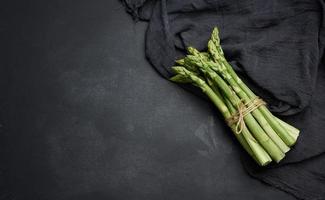 Fresh green asparagus sprouts on a black background. View from above photo