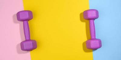 two purple plastic kilogram dumbbells on a bright colored background, top view. photo