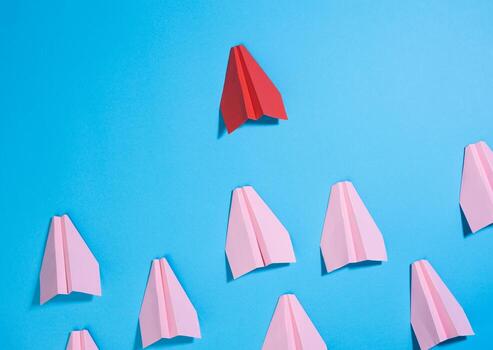 grupo de rosado papel aviones seguir el primero rojo en contra un azul antecedentes. el concepto de uniendo un equipo a lograr metas foto