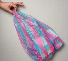 female hand holds full plastic bag on gray background, top view photo