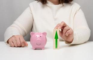 Pink ceramic piggy bank and wooden blocks with up arrow. Concept of increasing interest on a deposit in a bank photo