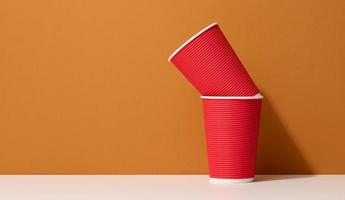paper cardboard red cups for coffee, orange background. Eco-friendly tableware