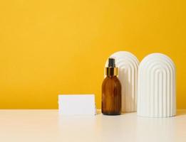 glass brown bottle with cosmetic spray on a yellow background photo