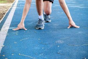 arm male touch floor start pose training running on track rubber blue in public park with copy space add text. Vintage toning. photo