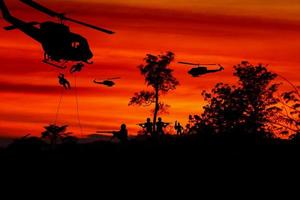 silueta soldados rappel abajo a ataque desde helicóptero con guerrero tener cuidado peligro en el suelo puesta de sol antecedentes difuminar y Copiar espacio añadir texto foto