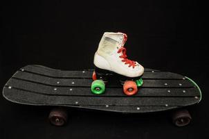 Roller skates and skateboard on black background photo