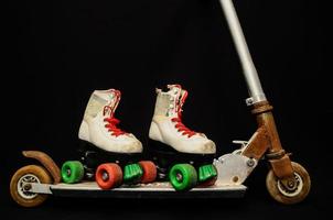 Roller skates and scooter on black background photo