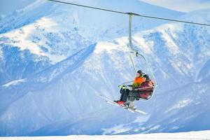 Gudauri, Georgia , 2022 - Elderly adventurous caucasian couple in ski chair lift together retired in winter ski resort on vacation photo