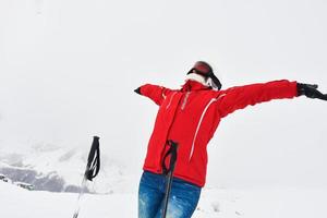 masculino persona en rojo chaqueta con esparcido manos mira a blanco montañas y Nevado blanco picos en el antecedentes. montañas abrazo concepto. foto