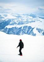 Young snowboarder ride downhill in scenic caucasus mountains in fast freeze motion steep downhill solo photo