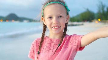 Adorable little girl making selfie at tropical white beach. SLOW MOTION video