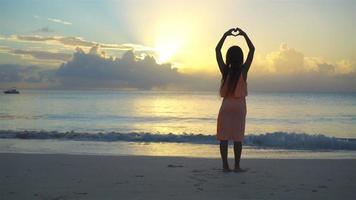 aanbiddelijk gelukkig weinig meisje hebben een veel van pret Aan wit strand Bij zonsondergang. video