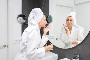 Positive lady applying cream in hotel bathroom photo