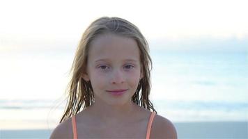 portret van weinig meisje op zoek Bij camera en glimlachen achtergrond mooi lucht en zee. langzaam beweging video