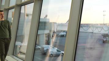 jong Mens binnen in luchthaven. Kaukasisch jongen Bij de luchthaven terwijl aan het wachten voor instappen. langzaam beweging video