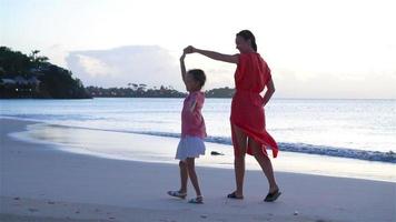 lindo mãe e filha em caribe de praia tendo Diversão dentro pôr do sol. família em de praia período de férias. lento movimento video