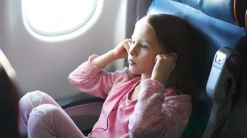 adorable niña viajando en avión. lindo niño con laptop cerca de la ventana en aviones video