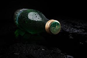 KRASNOYARSK, RUSSIA - NOVEMBER 01, 2022  A bottle of misted NARZAN mineral water on a black wet surface. photo