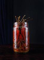 Glass jar with pickled chili peppers on black background photo