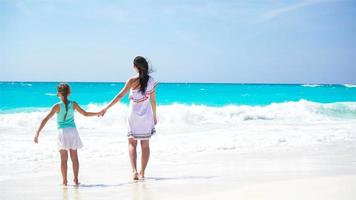 wenig bezaubernd Mädchen und jung Mutter beim tropisch Strand. Familie auf Karibik Ferien genießen das Meer Sicht. video