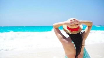 Back view of beautiful woman in hat on summer holidays on white beach. video