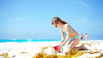 adorable peu fille en jouant avec jouets et fabrication le sable Château sur plage vacances video