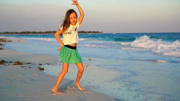 entzückendes glückliches kleines Mädchen am weißen Strand bei Sonnenuntergang video