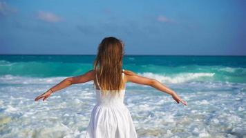 Adorable happy little girl on white beach looking on the ocean. Noisy sea and a small cute kid video