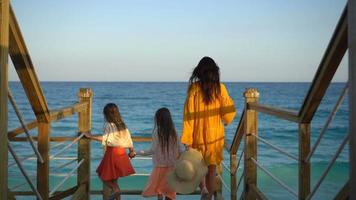 Adorable little girls and young mother walking on white beach in the evening video