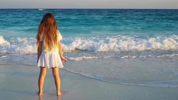 adorabile contento poco ragazza su bianca spiaggia a tramonto video