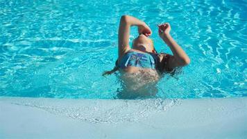 Portrait little girl having fun in outdoor swimming pool video