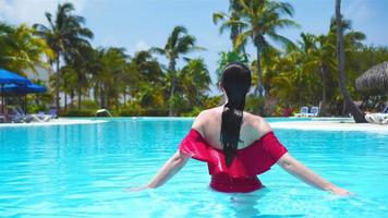 schöne junge frau, die im schwimmbad sich entspannt. glückliches Mädchen im Außenpool im Luxushotel video