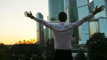 Back view of businessman looking on copy space while standing against glass skyscraper video