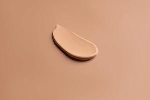 Make-up satin mousse foundation or bb-cream smudge. creamy beige stroke isolated on beige background photo