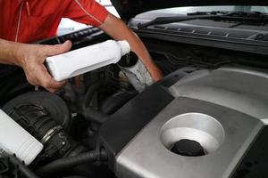 Close up hand adding fresh oil into engine car, repairing change the oil. Car maintenance at service station. photo
