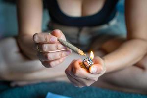 Women preparing lighting up marijuana joint with lighter. cannabis smoker rolling marijuana cannabis joint. Drugs narcotic concept. photo