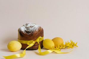 Set of traditional Russian and Ukrainian Easter cakes Kulich Paska bread sprinkled with powdered sugar whole, with yellow flowers, painted eggs, over the table. photo