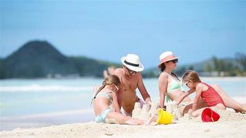 famiglia fabbricazione sabbia castello e godendo vacanza a tropicale bianca spiaggia video