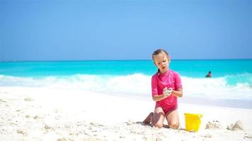 adorable petite fille jouant avec des jouets de plage sur la plage de sable blanc video