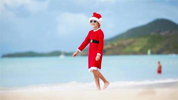 Back view of adorable girl in Christmas hat on the beach during Xmas vacation video