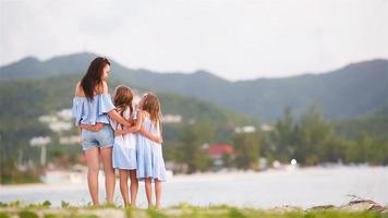 linda mãe e filhas na praia do caribe no pôr do sol. família em férias na praia. video